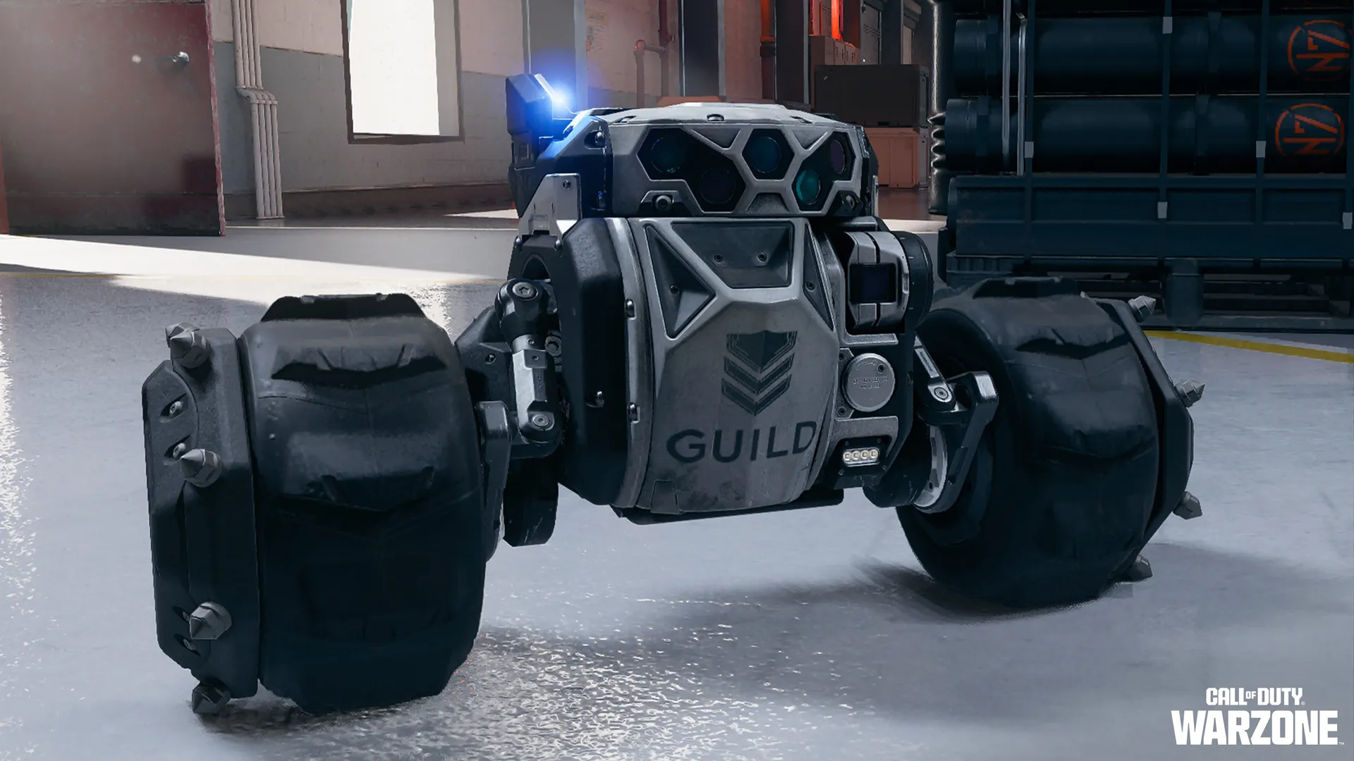 Compact four-wheeled robotic drone labeled GUILD with cameras and sensors on an industrial floor.