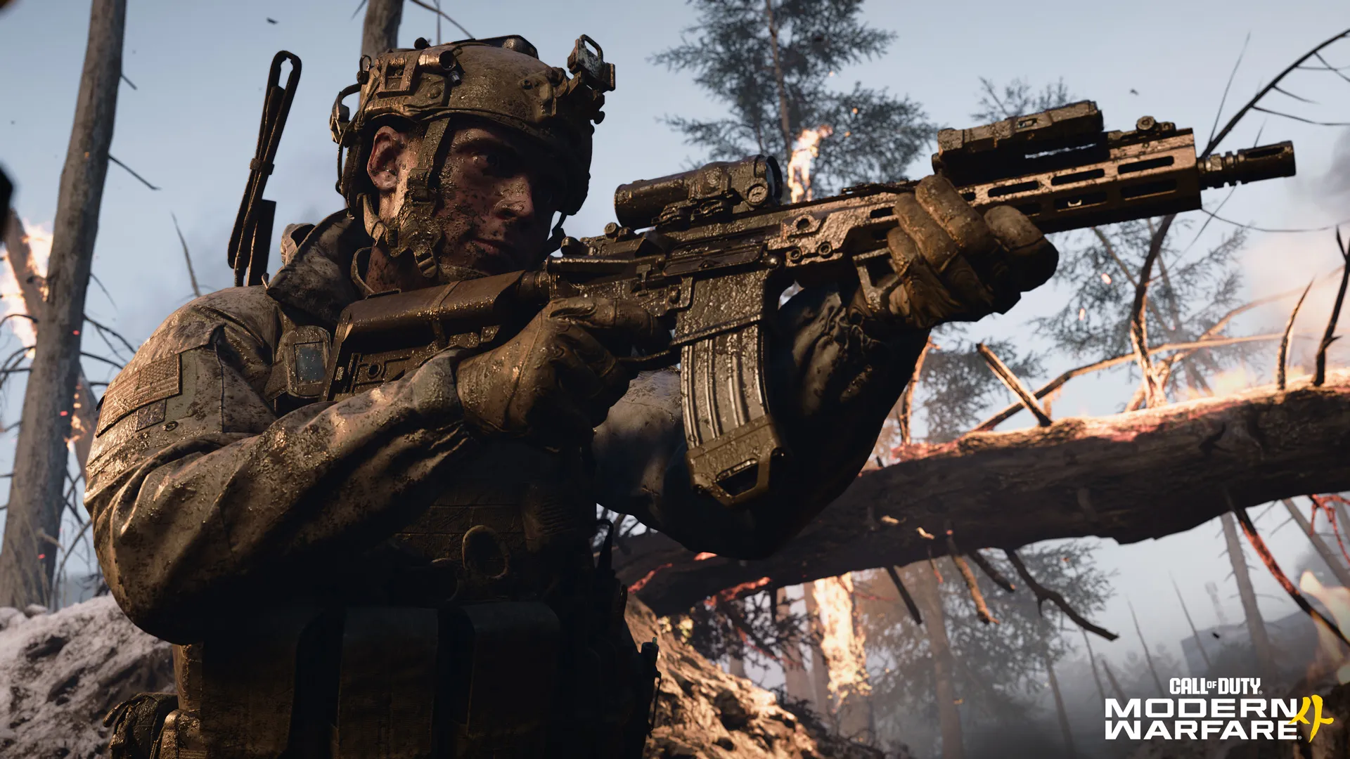A mud-covered soldier aims a rifle amid burning trees and battlefield debris.