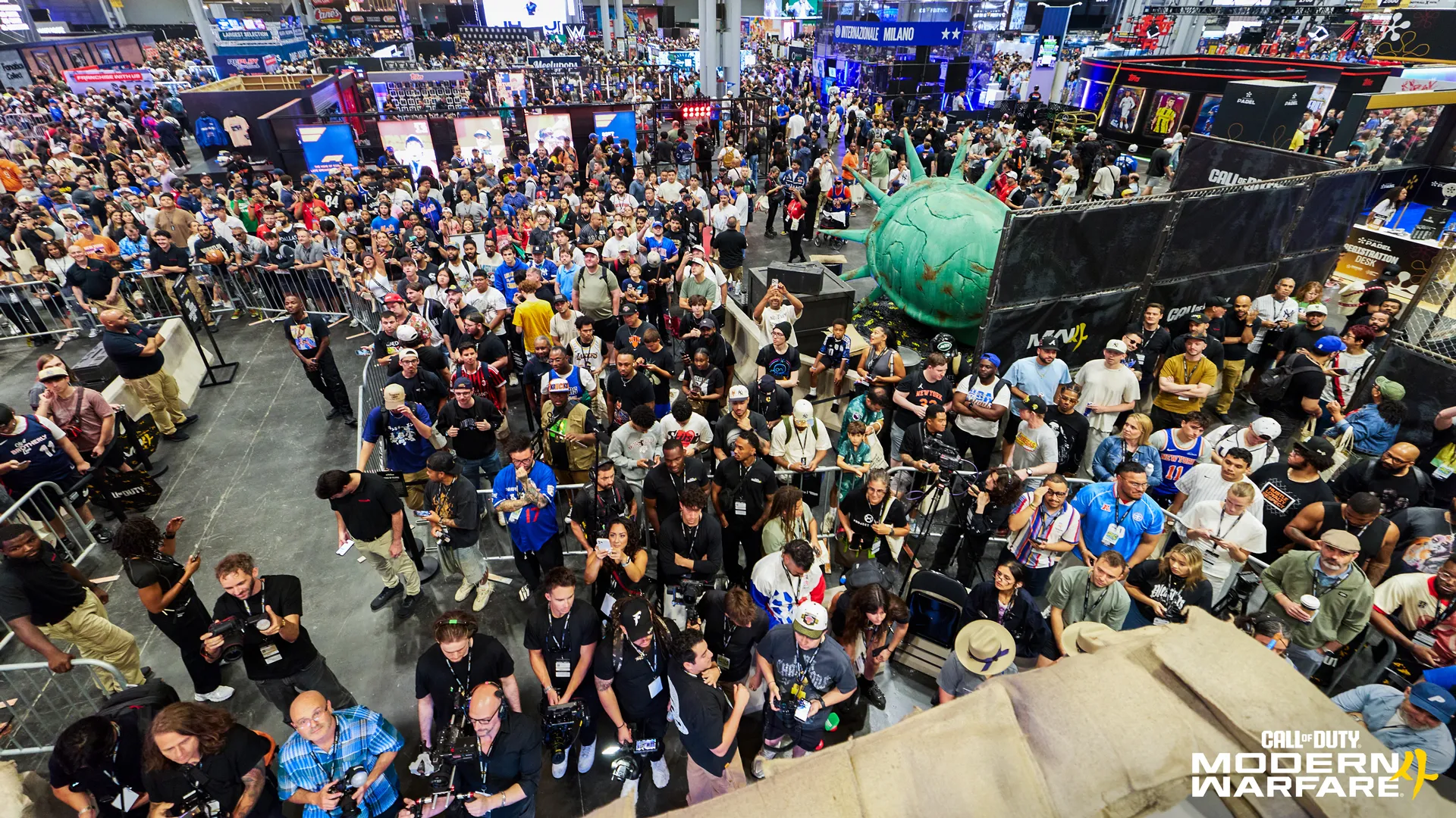 A large crowd fills the convention floor around the Call of Duty booth and a giant statue prop.