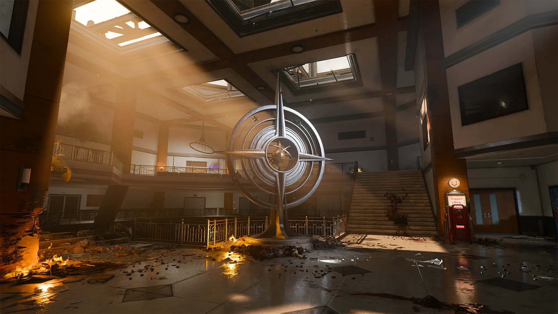 Beams of sunlight pour through broken skylights into a scorched lobby where a massive compass-shaped sculpture stands amid scattered debris, charred walls, and a bloody trail leading to a staircase.