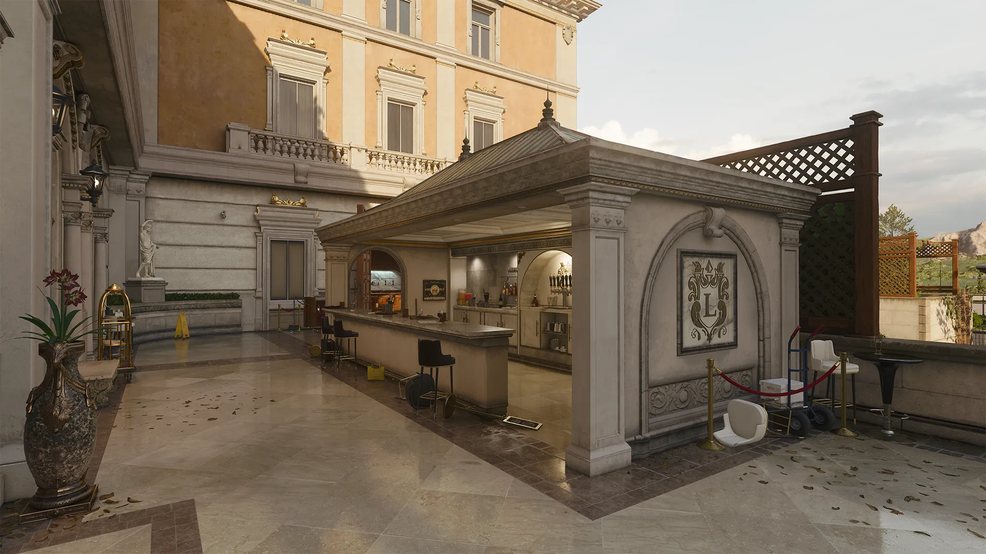 A covered outdoor bar with marble countertops sits against the side of a luxurious building, surrounded by statues, ornate tilework, and scattered lounge seating.