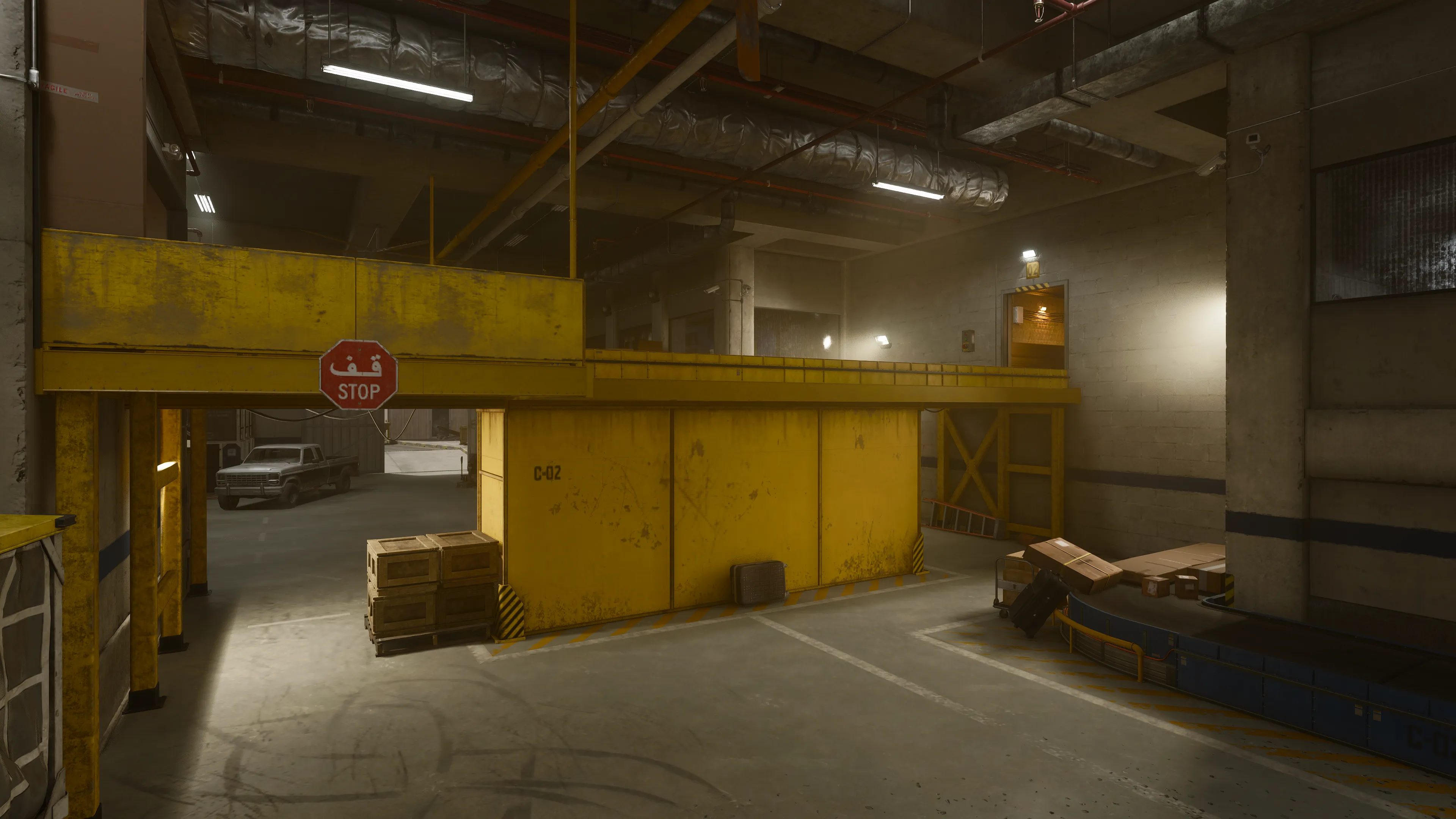 A yellow-painted cargo processing area beneath the airport features industrial signage, crates, and a stop sign in Arabic. (Description by ChatGPT)